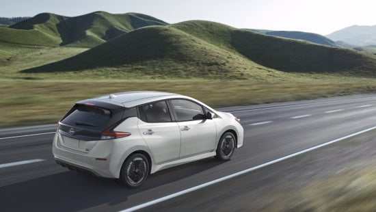 Nissan EV on the road with green hills in the background | Andy Mohr Avon Nissan in Avon IN