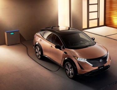 Nissan ARIYA plugged-in and charging outside a home | Andy Mohr Avon Nissan in Avon IN