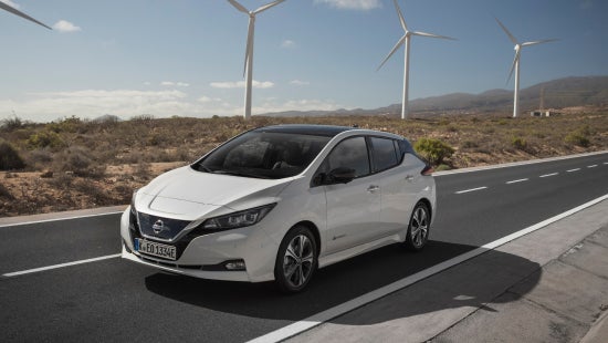 Nissan vehicle driving on road, wind turbines in the background | Andy Mohr Avon Nissan in Avon IN